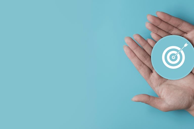 Hand holding blue paper cut with target icon