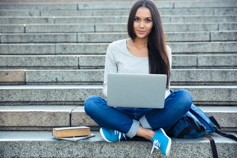 Young woman sitting on stairs and using laptop