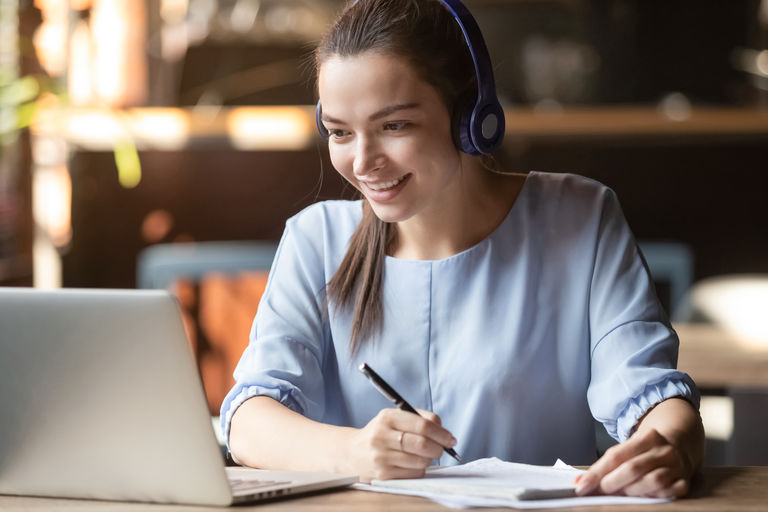 Smiling girl student wear wireless headphone study online with skype teacher