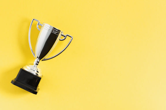 Winner or champion silver trophy cup on yellow background top view