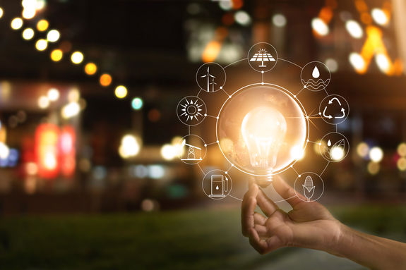 Hand holding light bulb in front of global show the world's consumption with icons energy sources for renewable, sustainable development. Ecology concept. Elements of this image furnished bSolvay One Planet
