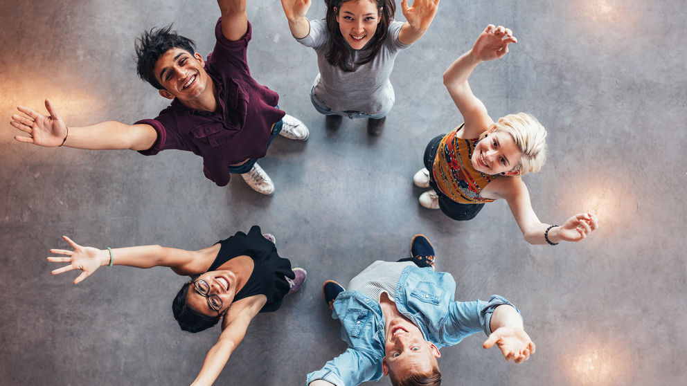 Top view of young students standing together looking up at camera with their hands raised in celebration Top view of young students standing together looking up at camera with their hands raised in celebration